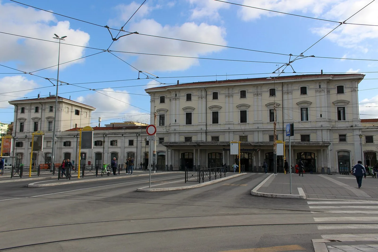 Facciata della stazione di Roma Trastevere con il piazzale antistante, le pensiline dei mezzi pubblici e i cavi del tram