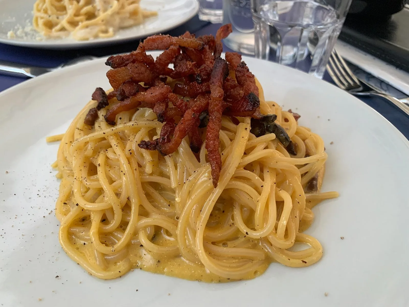 Piatto di spaghetti alla carbonara con guanciale croccante servito in un ristorante di Trastevere a Roma