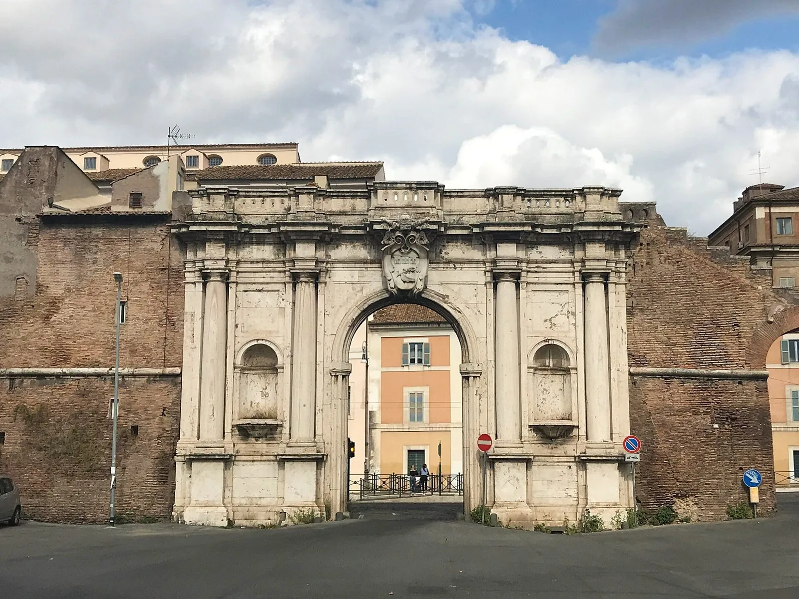 Porta Portese a Roma: l'arco barocco in pietra chiara con colonne, nicchie vuote e stemma papale, inserito nelle mura in laterizio
